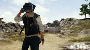 PUBG遊戲角色在岩石地形中調整頭盔，背景有破舊建築物。