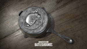 帶有PUBG標誌的金屬煎鍋在木質表面上