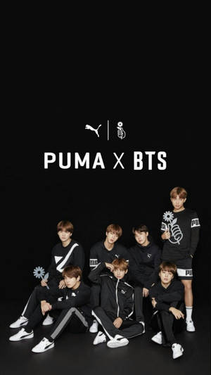 七名身穿黑色 Puma 服裝的 K-pop 偶像為品牌合作照片擺姿勢。