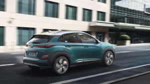 青綠色電動SUV在模糊建築的城市中快速行駛。 — 現代汽車 壁紙