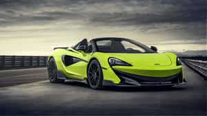 青檸綠色McLaren 570S Spider開篷跑車在多雲的天空下的高速公路上。 — 5120x2880 壁紙