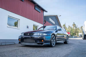陽光明媚嘅日子，黑色日產Skyline GT-R停喺工業大廈外面。 — 汽車 壁紙