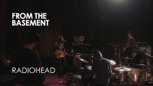Radiohead 在黑暗的地下場地中進行現場表演，配有舞台燈光。
