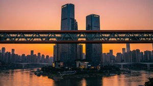 日落時，一座鋼橋橫跨河流，高樓大廈在水面反射出溫暖的色彩。