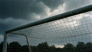 暴風雨天空下，足球龍門網在暴雨中，背景有樹木