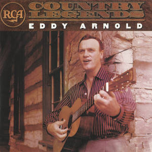 Eddy Arnold 在溫暖燈光下於木屋前彈結他。