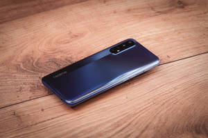 木桌上的藍色 realme 智能手機 — Realme 壁紙