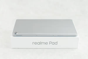 銀色 realme Pad 平板電腦放在白色盒子上，設計簡約。 — Realme 壁紙
