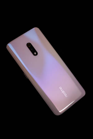 黑色背景上的粉紅色漸變 realme 智能手機。 — Realme 壁紙