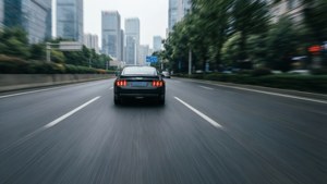 黑色跑車在濕漉漉的城市街道上飛馳，帶有動態模糊效果