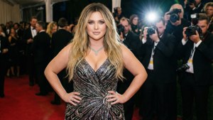 Khloé Kardashian 在一個華麗的活動中，在紅地毯上擺姿勢，身後有攝影師。