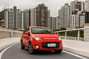 紅色Fiat Palio在城市高架橋上，背後有高樓大廈。 — MacBook Air M3 壁紙