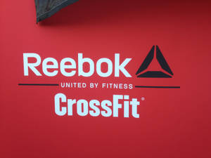 紅色牆壁帶有Reebok和CrossFit標誌及文字「因健身而團結」。