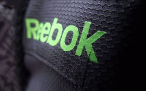 近距離拍攝黑色運動布料上的Reebok標誌。