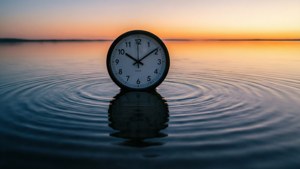 漂浮在水中的時鐘，帶有漣漪和夕陽倒影