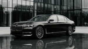 黑色BMW轎車停在濕瀝青路面上，反射玻璃建築