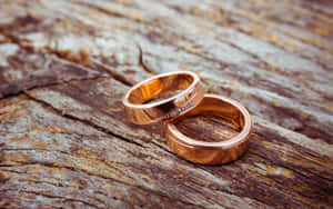 兩枚玫瑰金結婚戒指鑲有鑽石，放在質樸的木頭上。