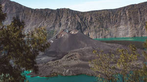 火山口，有綠松石色海水和岩石懸崖，以樹木為框架。 — 最佳 壁紙