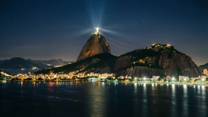 基督像在夜間於科爾科瓦多山頂亮起，俯瞰里約熱內盧的城市燈光和水面。