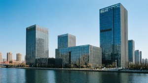 高聳的玻璃建築沿著平靜的河流排列，天空清澈湛藍。