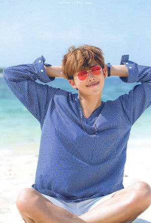 戴著紅色太陽眼鏡的年輕男子坐在陽光普照的海灘上