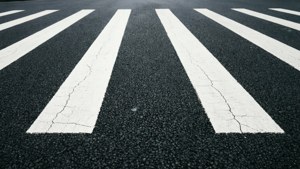 特寫磨損的行人過路處條紋在裂開的瀝青路面