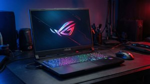 黑色ASUS ROG電競手提電腦，RGB鍵盤，在黑暗桌上，藍色和紅色燈光下
