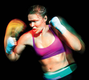身穿紫色運動胸罩的女拳擊手以動態模糊效果揮出一拳。