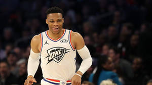 身穿白色OKC球衣的籃球運動員在比賽中微笑。