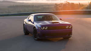 金色夕陽下賽車場上的紫色Dodge Challenger，車頭燈閃爍。