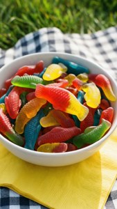 野餐墊上白色碗裡色彩繽紛的軟糖魚。