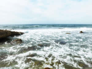 海浪在部分多雲的天空下拍打深色岩石