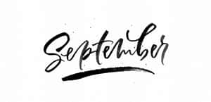 在白色紋理紙張上以粗體黑色毛筆書法書寫的「September」一詞。