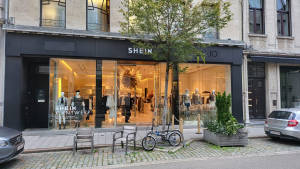 SHEIN時裝店正面，夜間鵝卵石行人路上有人體模型和單車。
