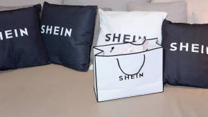 白色SHEIN購物袋在梳化上，配有品牌枕頭。