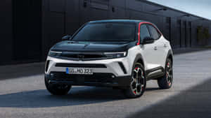 白色和黑色歐寶SUV，帶紅色飾邊，停在工業建築前。 — Oppo 壁紙