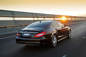 黑色Mercedes CLS Coupe在金色日落時分於高速公路疾馳。 — Surface Pro 壁紙