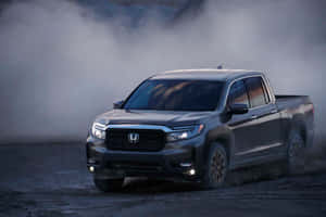 灰色本田Ridgeline皮卡車在塵土飛揚的地形上行駛，伴有煙霧。 — MacBook 壁紙
