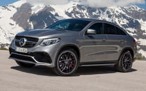 銀色Mercedes-AMG GLE63 S Coupe停泊在山路上，背景是白雪覆蓋的山峰。 — Steam Deck OLED 壁紙