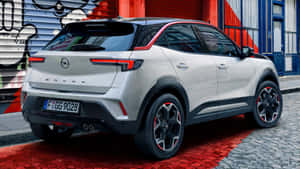 銀色Opel Mokka SUV停泊在紅色鵝卵石街道上，靠近塗鴉牆。 — Oppo 壁紙