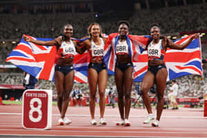四位英國女運動員手持英國國旗慶祝勝利。 — MacBook Pro 壁紙