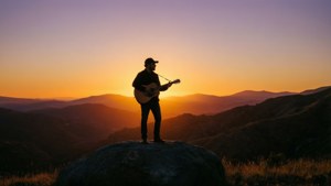 音樂家在金色夕陽下的山頂彈結他