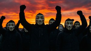 戴蓋伊·福克斯面具的人在日落抗議中舉起拳頭