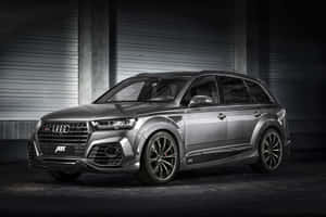 銀色ABT Audi SQ8 SUV停在有混凝土牆的黑暗工業車庫中。 — Surface Pro 壁紙