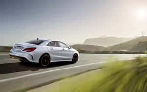 銀色 Mercedes-Benz CLA 轎車在日落時分的山路上疾馳。 — Steam Deck 壁紙