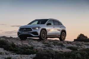 日落時岩石地形上的銀色Mercedes-Benz SUV — Surface Pro 壁紙