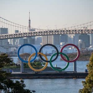 水邊的奧運五環，背景有東京塔和彩虹橋。