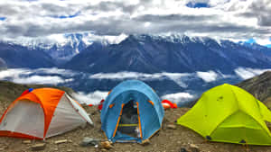 在高山上搭建的彩色帳篷，俯瞰著白雪覆蓋的山峰和雲海。