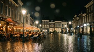 人們在歷史悠久的歐洲城鎮廣場的雨夜，在戶外咖啡館用餐。