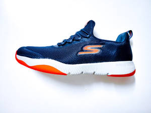 一雙藍色Skechers運動鞋，在白色表面上帶有橙色和白色細節。